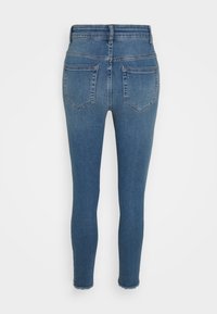 Jeans de ganga azul ajustados com uma cintura alta, apresentando uma bainha desfiada, dois bolsos traseiros e uma textura suave.