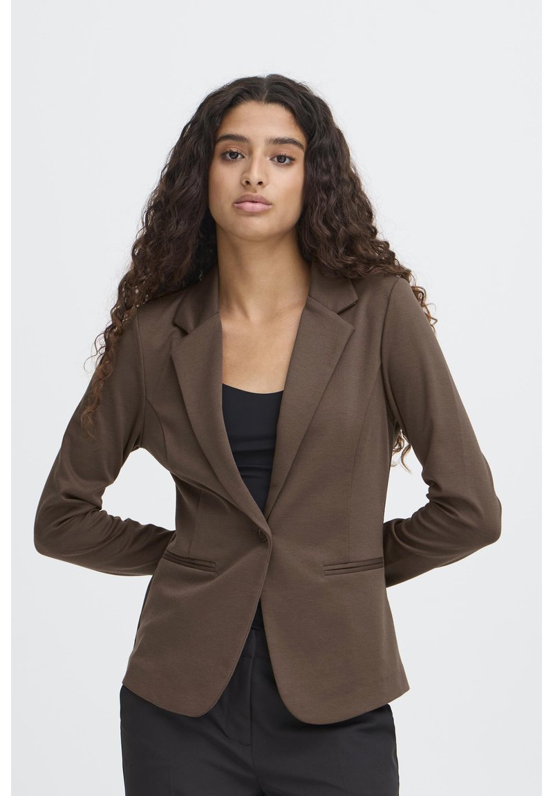 Brun skräddarsydd kavaj med nedvikt slag, två framfickor och en figurnära silhuett. Tillverkad av ett slätt tyg i enfärgat.