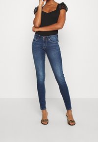 Mörk denim skinny jeans med hög midja, som har en klassisk femfickorsdesign, subtil blekning och en blå nyans.