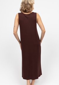 Vestido maxi sin mangas en color marrón, fabricado en un tejido suave, con un escote redondo y una silueta suave y fluida, que llega hasta la mitad de la pantorrilla.