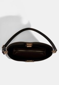 Sac à main en cuir noir avec un fermoir et une fermeture éclair dorés, texture lisse et une seule poignée. L'intérieur possède un compartiment zippé.