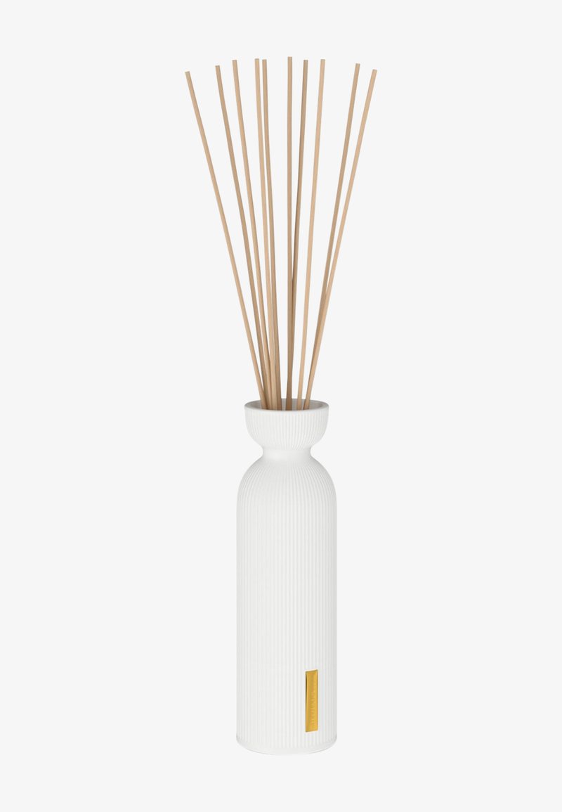 Hvit keramisk diffuservase med ribbet tekstur og fem beige reed-pinner, med en liten gullaccent på forsiden.