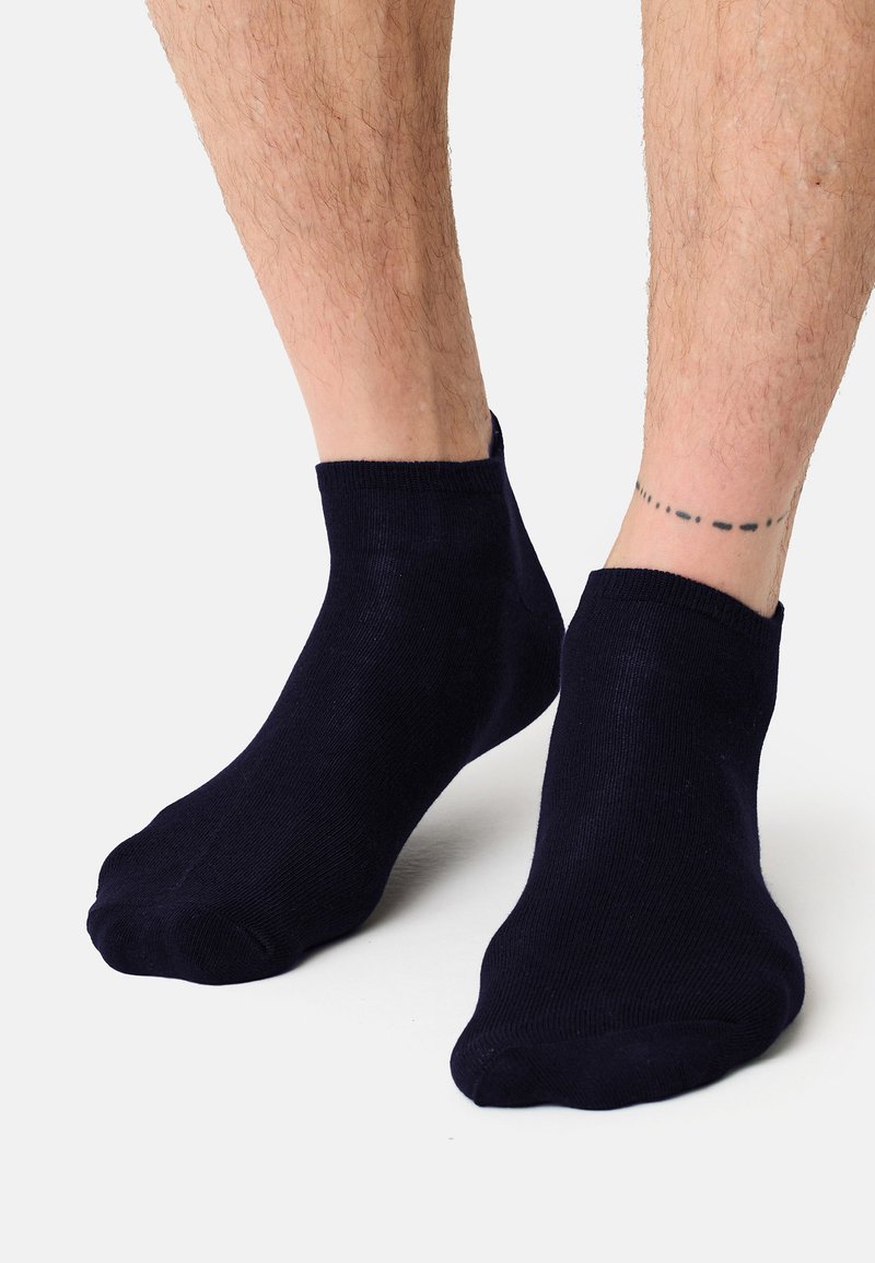 Calcetines tobilleros azul marino en un material suave y elástico con textura lisa y puño acanalado, diseñados para un ajuste ceñido.