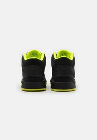 Czarne sneakersy z teksturowaną cholewką, jasne żółte akcenty oraz formowanym obcasem z wytłoczonym napisem "Timberland" z tyłu.