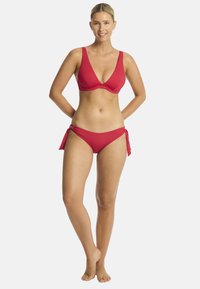 Rode bikini met een driehoekige bralette met brede bandjes en een bijpassende low-rise slip met zijstrikjes. Glad stoftextuur.