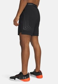 Černé atletické šortky s texturovaným páskem a potiskem na straně. V kombinaci s černými a oranžovými nízkými teniskami.