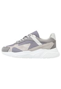 Sneakers gris avec une combinaison de cuir suédé et de mesh, une semelle en caoutchouc blanc, des accents texturés et un design sportif avec fermeture à lacets.