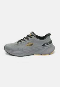 Scarpa da ginnastica grigia con tomaia in rete, dettagli neri, accenti gialli e suola testurizzata. Presenta un design slip-on con collarino imbottito.
