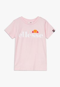 Světle růžové bavlněné tričko se velkým bílým logem "ellesse" a barevným polokruhovým grafickým prvkem; krátké rukávy a kulatý výstřih.