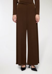 Pantaloni a gamba larga marroni realizzati in un tessuto liscio, con una vita nascosta e un accento decorativo dorato sul lato.