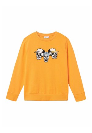 Oranje sweatshirt met een afbeelding van drie schedels die hoeden dragen. Het heeft lange mouwen, een ronde halslijn en ribgebreide manchetten en onderkant.