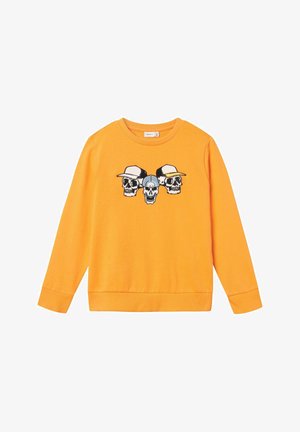 Sweatshirt orange avec un graphique de trois crânes portant des chapeaux. Il a des manches longues, un col rond et des poignets et un ourlet côtelés.