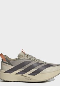 Μπεζ και γκρι παπούτσι για τρέξιμο Adidas με μαύρες ρίγες, δέσιμο με κορδόνια και παχιά σόλα με την ένδειξη Lightstrike Pro, μοντέλο Adizero Evo SL ATR.