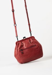 Rode leren handtas met een ronde vorm, geplooide textuur en een voorzak met rits. Verstelbare schouderband met zwarte hardware accenten.