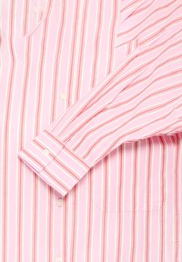 Chemise rose à boutons avec des rayures verticales dans des tons de rose et de rouge, dotée d'une poche, d'un col pointu et de longues manches avec poignets.