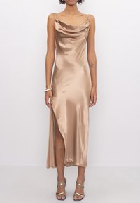 Robe en satin avec décolleté drapé, beige, dotée d'une fente haute sur la cuisse. Bretelles spaghetti et texture lisse. Assortie avec des escarpins à lanières.