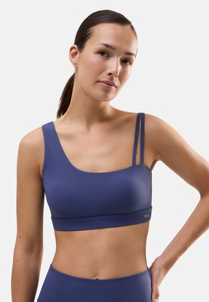 Sujeción deportiva de color azul marino con escote redondeado, una tirante en el hombro y tirantes dobles. Tejido suave con un logo en la banda.