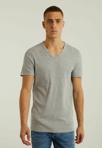 Tricou din bumbac gri cu decolteu în V, cu mâneci scurte, o siluetă ajustată și un detaliu mic cu logo pe mânecă.