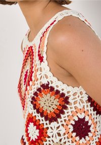 Gehaakte mouwloze top met een meerkleurig patroon in rood, oranje, beige en wit, met geschulpte randen en opengewerkte details.