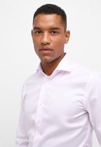 Camicia da uomo fitted di colore viola chiaro, con colletto rigido, chiusura con bottoni, tessuto strutturato e finitura liscia su uno sfondo neutro.