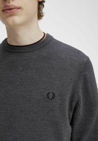 Maglione grigio a maglia con scollo a girocollo e colletto a coste marrone. Presenta un piccolo logo ricamato nero sul lato sinistro del petto.