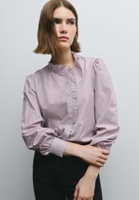 Red and white striped blouse with a ruffled neckline and cuffs, single button closure, featuring long puffy sleeves and a fitted waist.