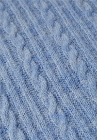 Tissu en laine bleu doux avec un motif en tricot torsadé surélevé comprenant des textures verticales tressées et côtelées.