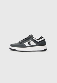 Niskie sneakersy w kolorze czarnym i białym z czarnymi sznurowadłami, perforowanym przodem, teksturowanym panelem bocznym oraz nadrukowanym logo na boku.