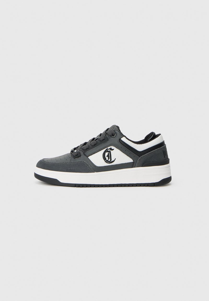 Niskie sneakersy w kolorze czarnym i białym z czarnymi sznurowadłami, perforowanym przodem, teksturowanym panelem bocznym oraz nadrukowanym logo na boku.