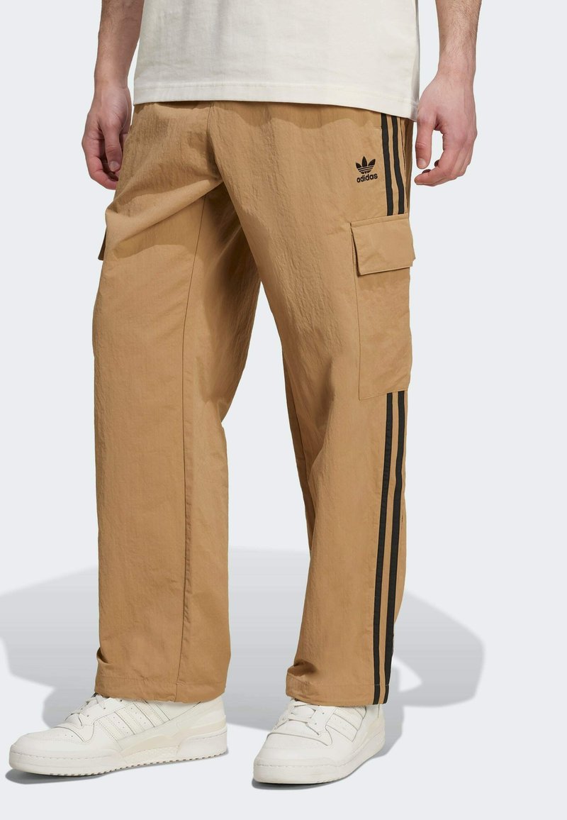 Pantalon cargo beige en tissu léger avec des bandes latérales noires, une poche sur la cuisse et une finition subtilement texturée.
