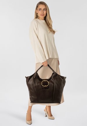 Borsa tote in pelle marrone con grande fibbia circolare dorata. Texture liscia, forma ampia e manici robusti per un facile trasporto.
