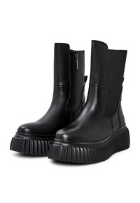 Botas de tobillo de cuero sintético negro con paneles laterales elásticos, cierre de cremallera y suela gruesa con estrías. Diseño elegante y moderno con un acabado mate.