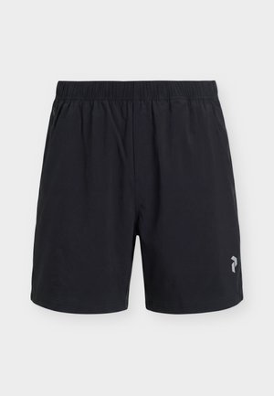 Short de sport noir avec taille élastique, poches latérales et petit logo réfléchissant sur la jambe inférieure droite.