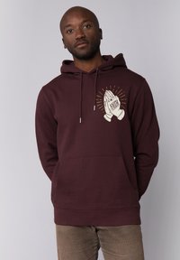 Bordeaux hoodie met een voorzak, voorzien van een bedrukte grafiek van ineengeregen handen en het woord "FAITH" in een contrasterende kleur.