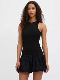 Črna brezrokavna rebrasta majica, kombinirana z obsežno črno krilo, ki ima nabran teksturo in elastičen pas.