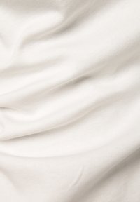 White cotton fabric with a smooth, slightly textured surface, featuring soft folds and creases, highlighting its drape and lightweight quality.