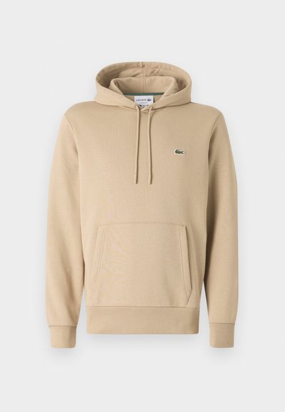 Sweatshirt à capuche beige fabriqué en mélange de coton. Il dispose d'une poche kangourou, de poignets côtelés et d'un petit logo brodé vert sur la poitrine.