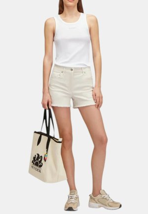 Top a canottiera bianca a coste, pantaloni shorts in denim beige chiaro con orlo sfrangiato e sneakers beige. Borsa a tracolla beige con logo nero e dettagli in perline colorate.