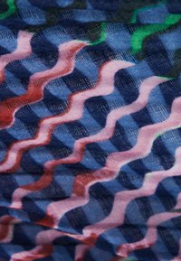 Tessuto colorato con motivo a onde in tonalità di rosa, rosso e blu, con una superficie testurizzata e un delicato disegno a quadretti.