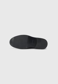 Talpa de pantof negru cu o suprafață netedă și plată, cu vârful rotunjit. Design minimalist, fără modele sau embellishments vizibile.