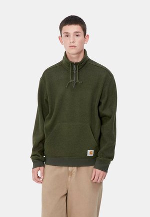 Camiseta de felpa verde oliva con cuello de media cremallera, detalle de cordón y bolsillo tipo canguro en la parte delantera. Presenta puños y dobladillo de canalé.