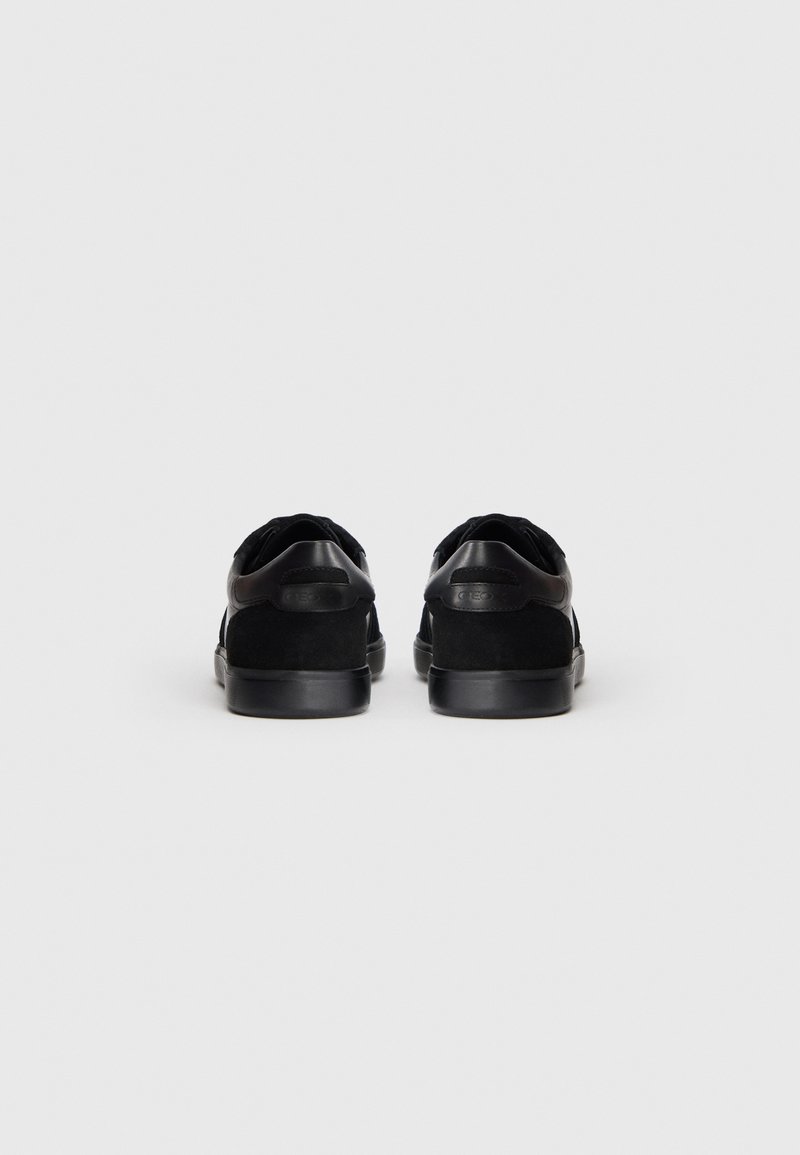 Zapatillas negras con parte superior de ante y sintético texturizado, diseño de punta redondeada y suelas de goma planas. Detalles mínimos en la parte trasera.