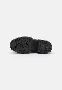 Suola di scarpa in gomma nera con un motivo di battistrada robusto, caratterizzato da tacche incrociate e un piccolo accento blu vicino al tallone. Superficie testurizzata.