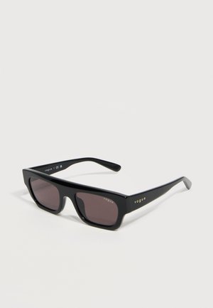 Crne pravokutne Vogue sunčane naočale s tamnim nijansiranim staklima i tankim okvirom, prikazane na svijetloj jednobojnoj pozadini.