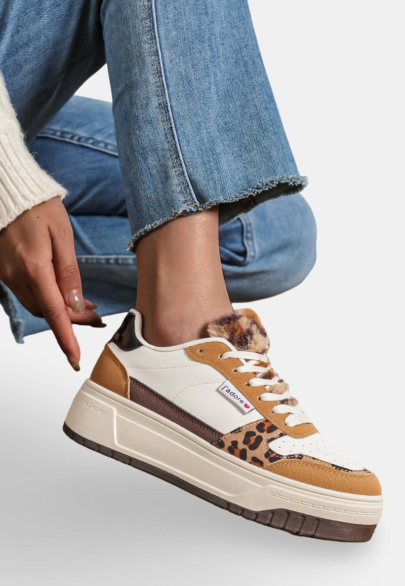 Les sneakers présentent une base en cuir blanc avec des accents en suède marron et un imprimé léopard. Semelle épaisse, collier en fourrure et lacets crème.