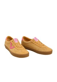 Paar senfgelbe Wildleder-Vans-Sneaker mit pinken Akzenten, braunen Gummisohlen und dem "Vans Off The Wall"-Logo auf der Zunge.