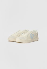 Beige sneakers with light blue accents, featuring a textured surface, lace-up front, and star logo on the side. Curved, low-profile design.