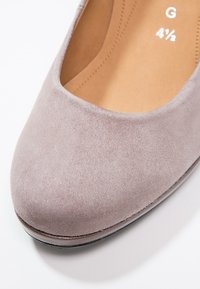 Chaussure plate en daim gris clair avec bout arrondi, taille 4½, semelle intérieure cousue et petit talon noir visible sur fond blanc.