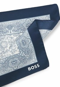Sciarpa di seta blu navy con motivo paisley azzurro chiaro e logo "BOSS" bianco nell'angolo. I bordi sono rifiniti con cura.