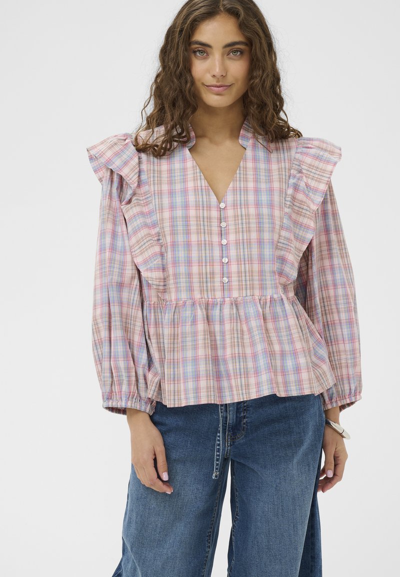 Blouse légère à carreaux avec un profond décolleté en V, des épaules volantées et une fermeture à boutons sur le devant. Couleurs : rose, bleu et beige.
